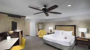 A hotel room with a bed, desk, chair, and a ceiling fan.