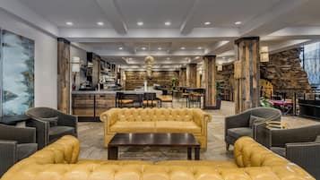 A spacious lobby with a central seating area, a bar, and a stone accent wall.