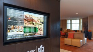A Courtyard Marriott hotel lobby with a large digital display, comfortable seating, and a view of the lobby area. - Courtyard Marriott Laredo (Laredo)