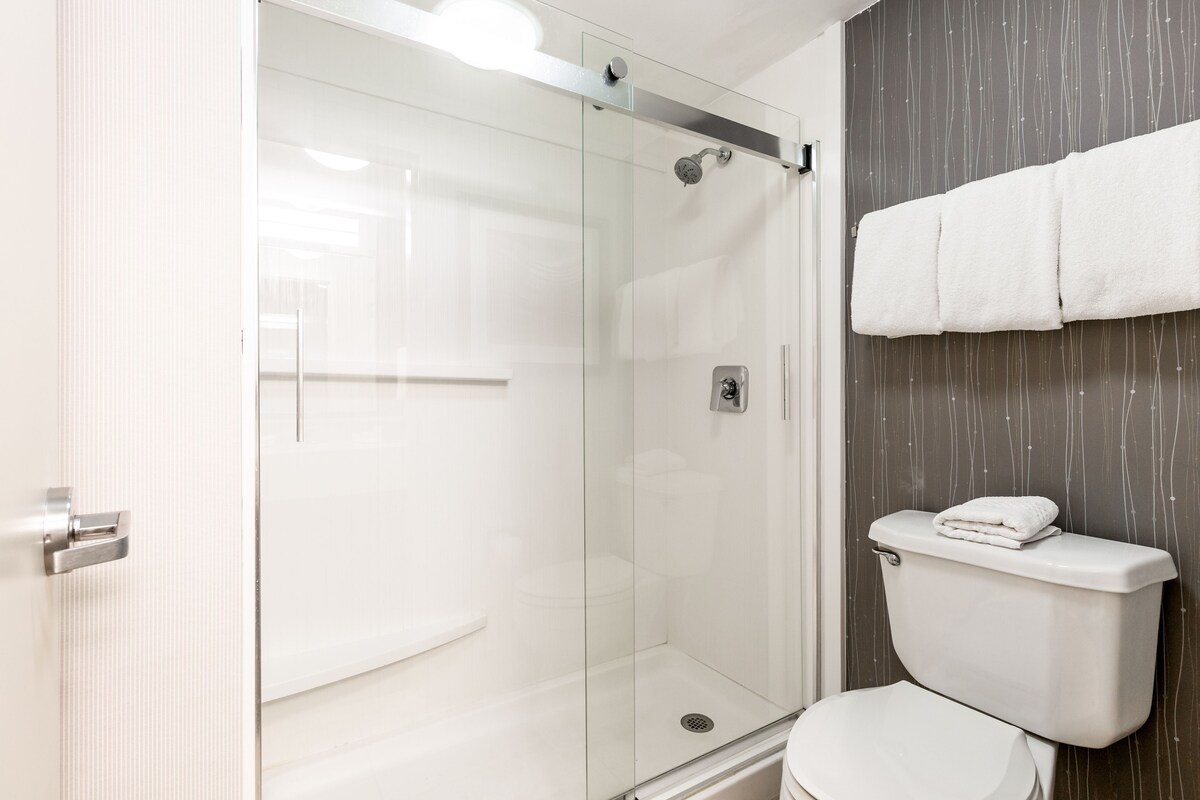 Ein modernes Badezimmer mit einer Duschkabine, einer weißen Toilette und einem Handtuchhalter.