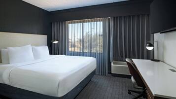 Habitación de hotel con una cama grande, un escritorio y una ventana con cortinas.