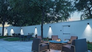 An outdoor patio with a fire pit, seating area, and ambient lighting. - Courtyard Marriott Laredo (Laredo)