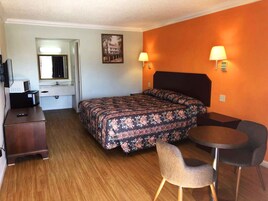 Una habitación de hotel con cama, escritorio, silla y una pequeña mesa.