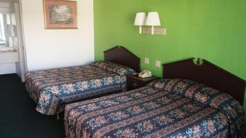 Una habitación con dos camas individuales, una mesita de noche con lámpara y un cuadro enmarcado en la pared.