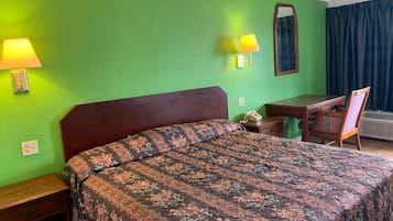 Habitación de hotel con cama, escritorio, silla y espejo.