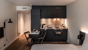 A compact hotel room with a kitchenette, a dining area, and a bed. - pentahotel Wiesbaden (Wiesbaden)