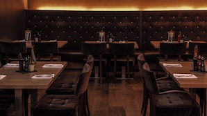 A restaurant with dark wood furniture, a tufted backrest, and a warm ambient light. - pentahotel Wiesbaden (Wiesbaden)