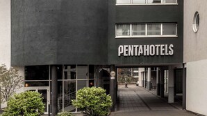 A modern penthouse hotel with a curved facade, large windows, and a clear sky. - pentahotel Wiesbaden (Wiesbaden)