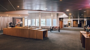 A spacious hotel lobby with a central reception desk, large windows, and a patterned carpet. - pentahotel Wiesbaden (Wiesbaden)
