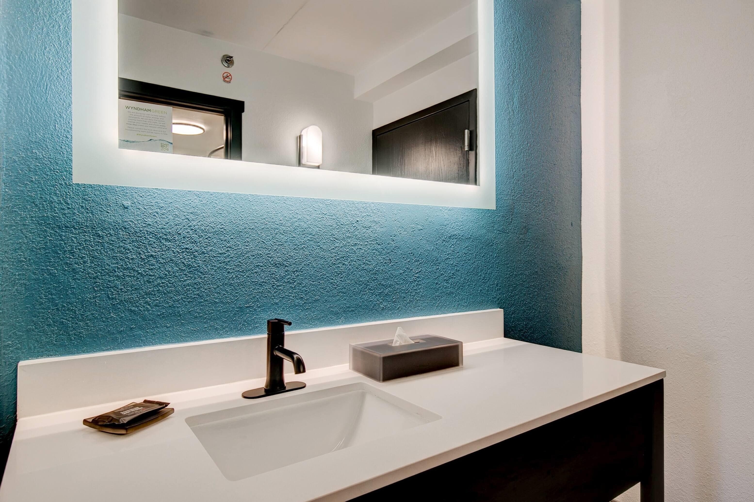 Une salle de bain avec un lavabo blanc, un robinet noir et un porte-mouchoirs.