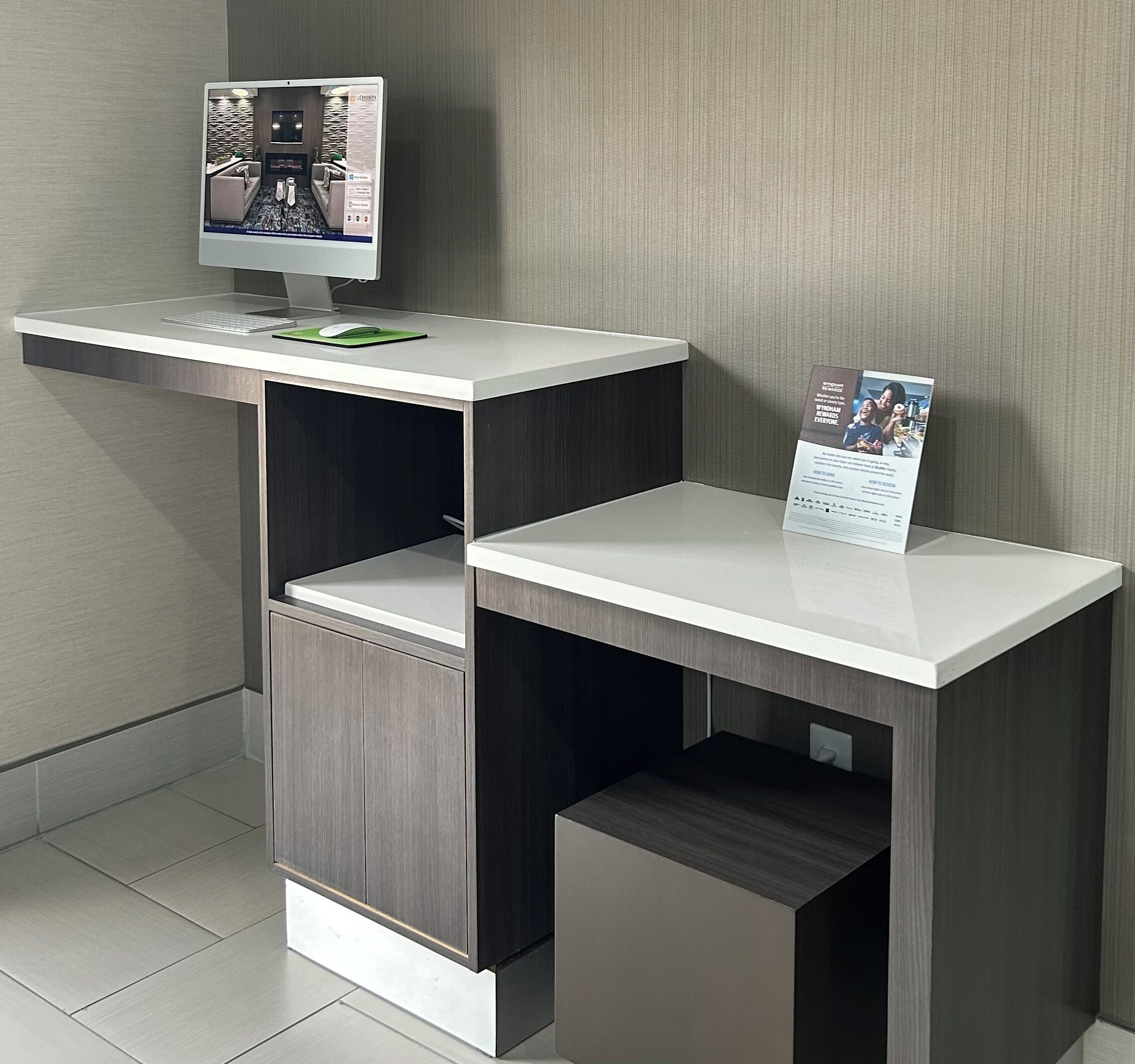 Una moderna reception hoteliera con un monitor computer, uno scaffale piccolo e un espositore per brochure.