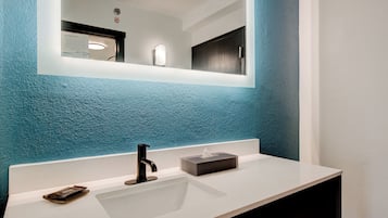 A modern bathroom with a white sink, black faucet, and a mirror above it.