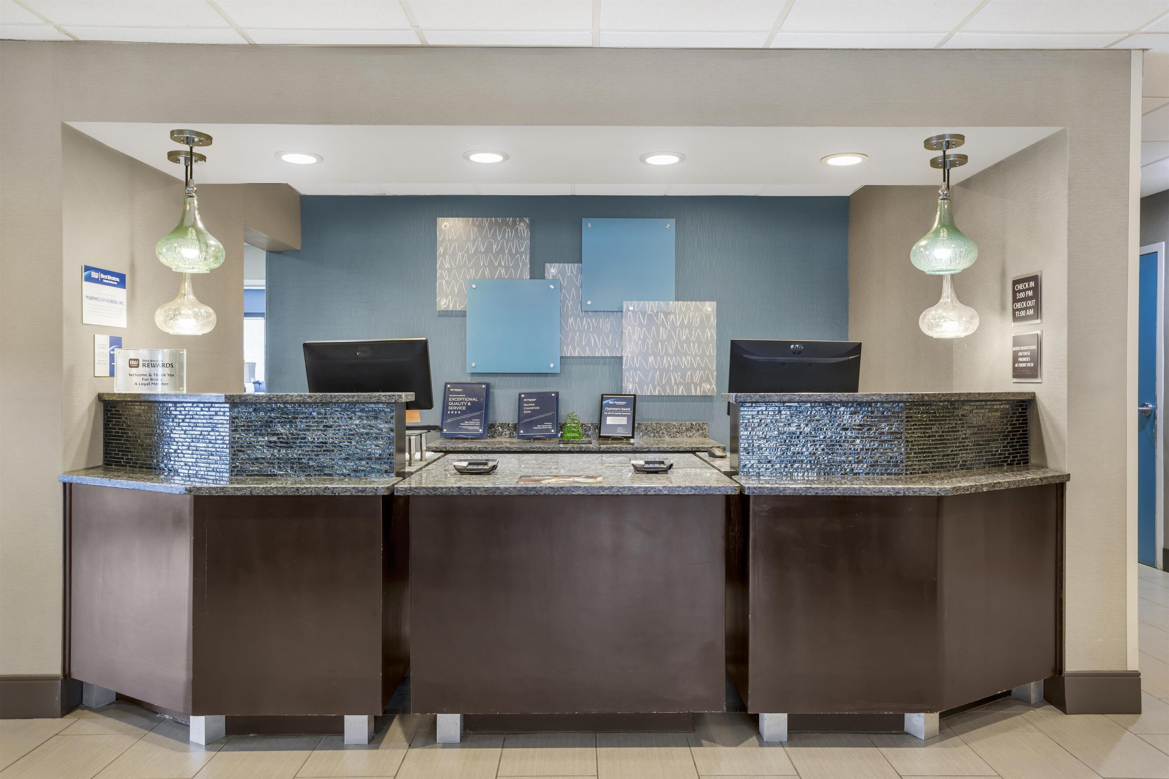A reception area with a modern design, featuring a dark reception desk, a blue accent wall, and decorative wall art.