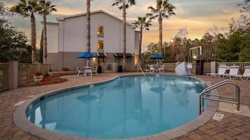 Een buitenzwembad, parasols bij het zwembad en ligstoelen
