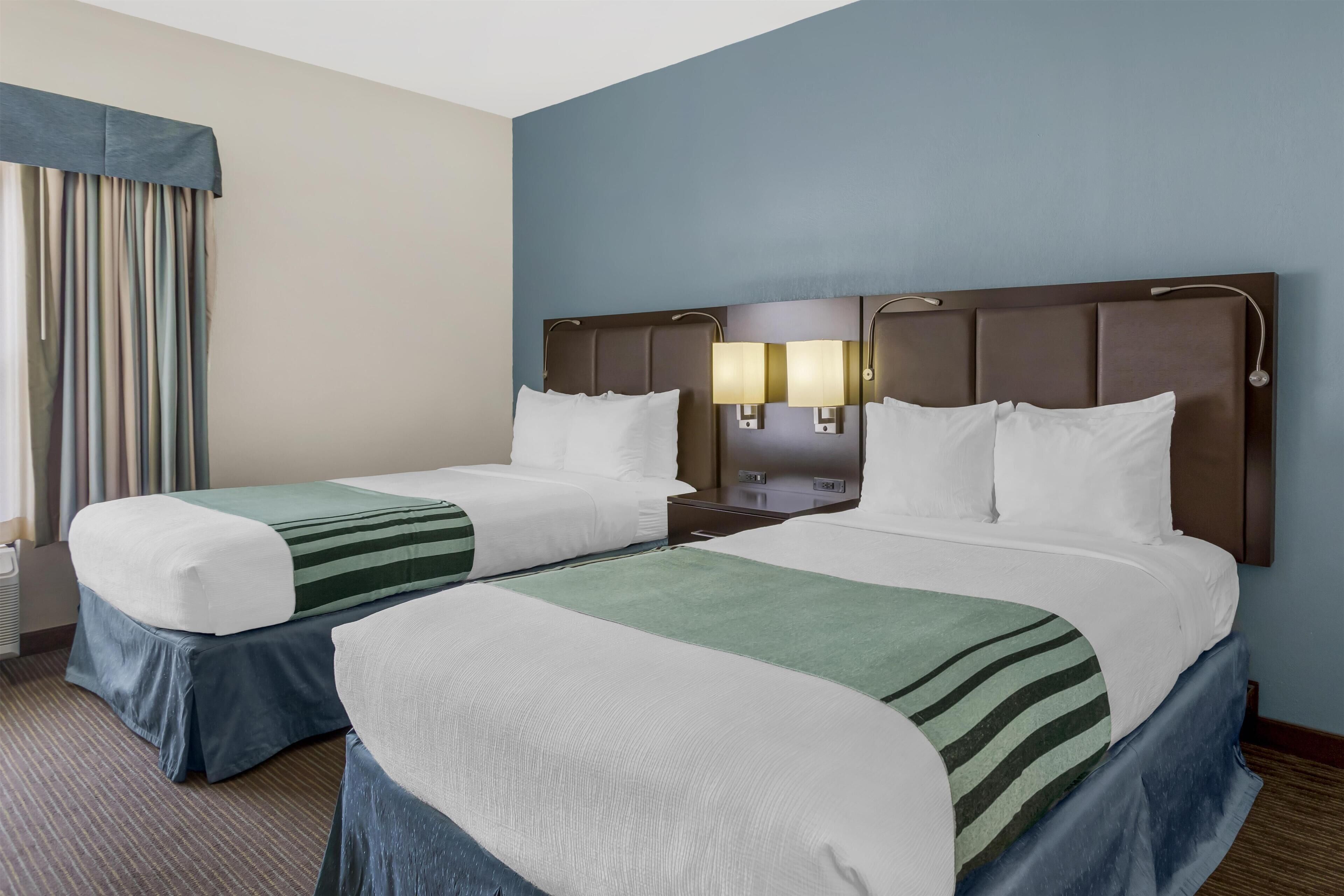 Une chambre d’hôtel avec deux lits, une table de chevet et une lampe.