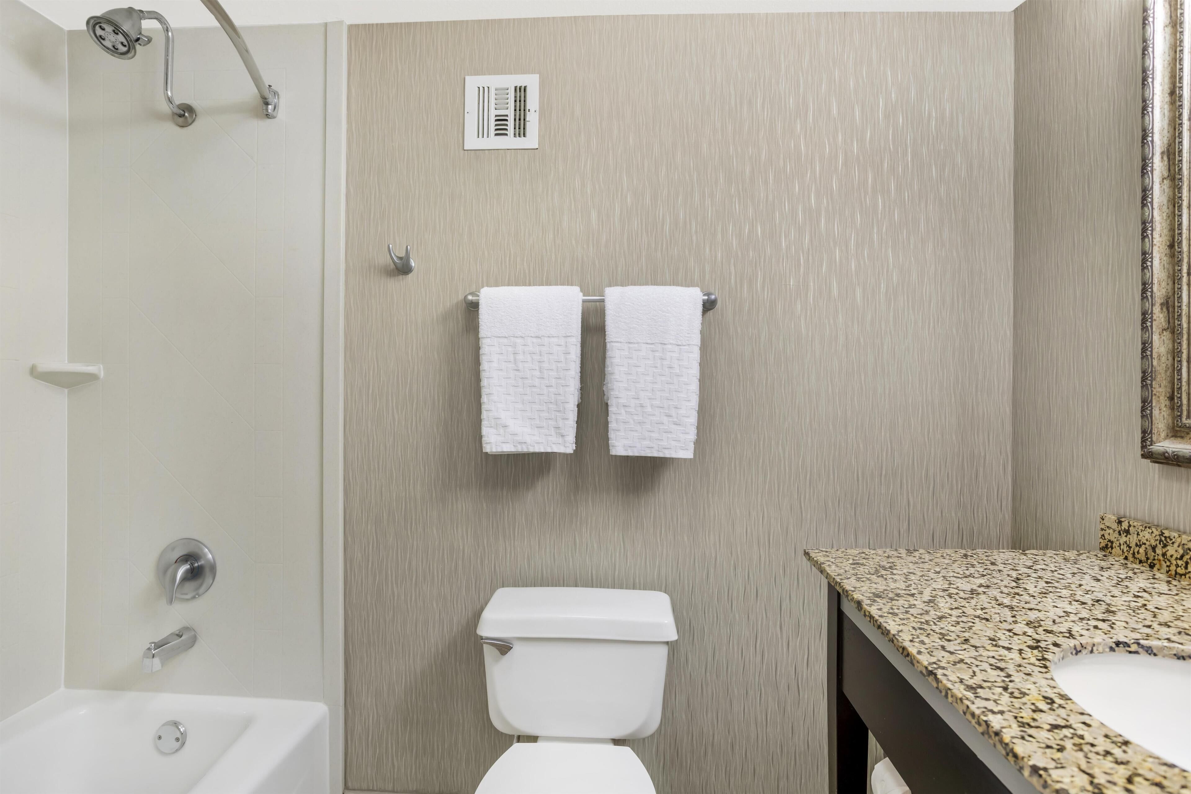 A bathroom with a shower, toilet, sink, and towel rack.