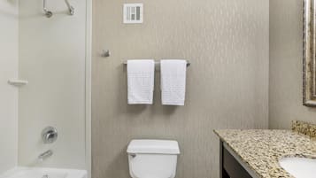 A bathroom with a shower, toilet, sink, and towel rack.