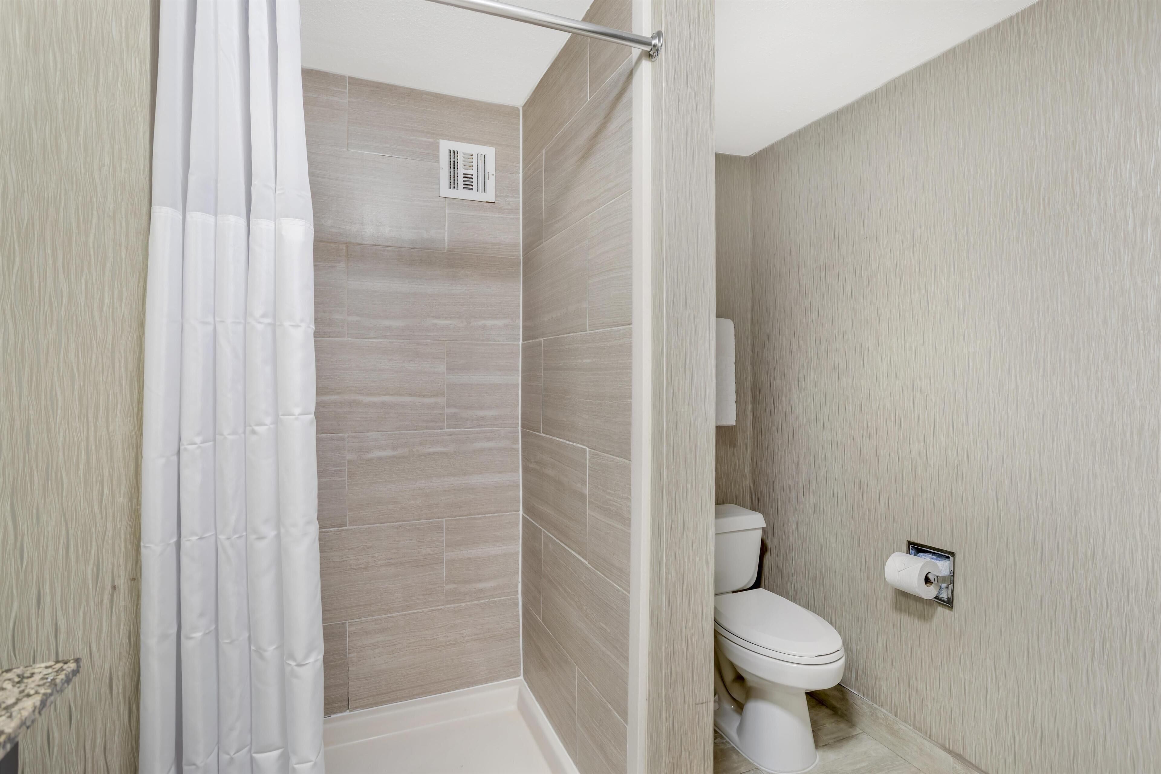 A modern bathroom with a shower, toilet, and a towel rack.