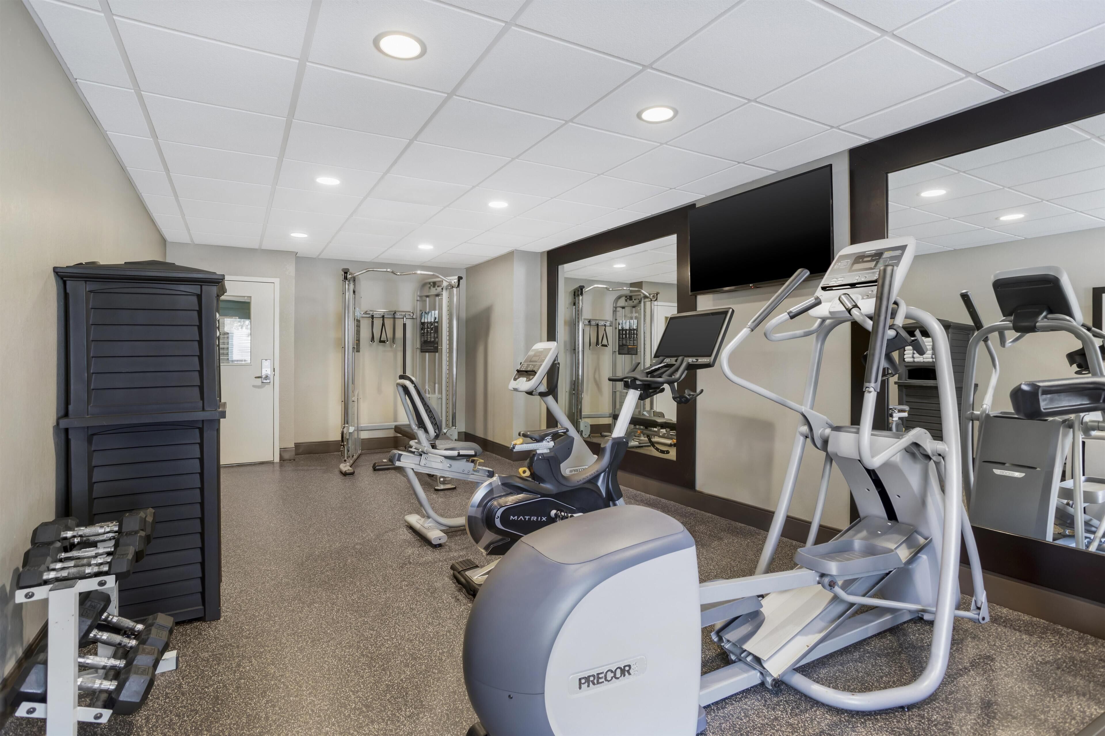 A gym with treadmills, elliptical machines, and free weights.