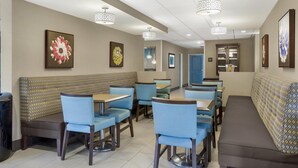 Een restaurant met zitplaatsen, tafels, plafondlampen en wanddecoratie.