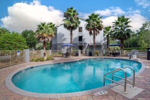 Una piscina al aire libre, sombrillas, sillones reclinables de piscina