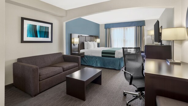 Een hotelkamer met een bed, een slaapbank, een bureau en een stoel.