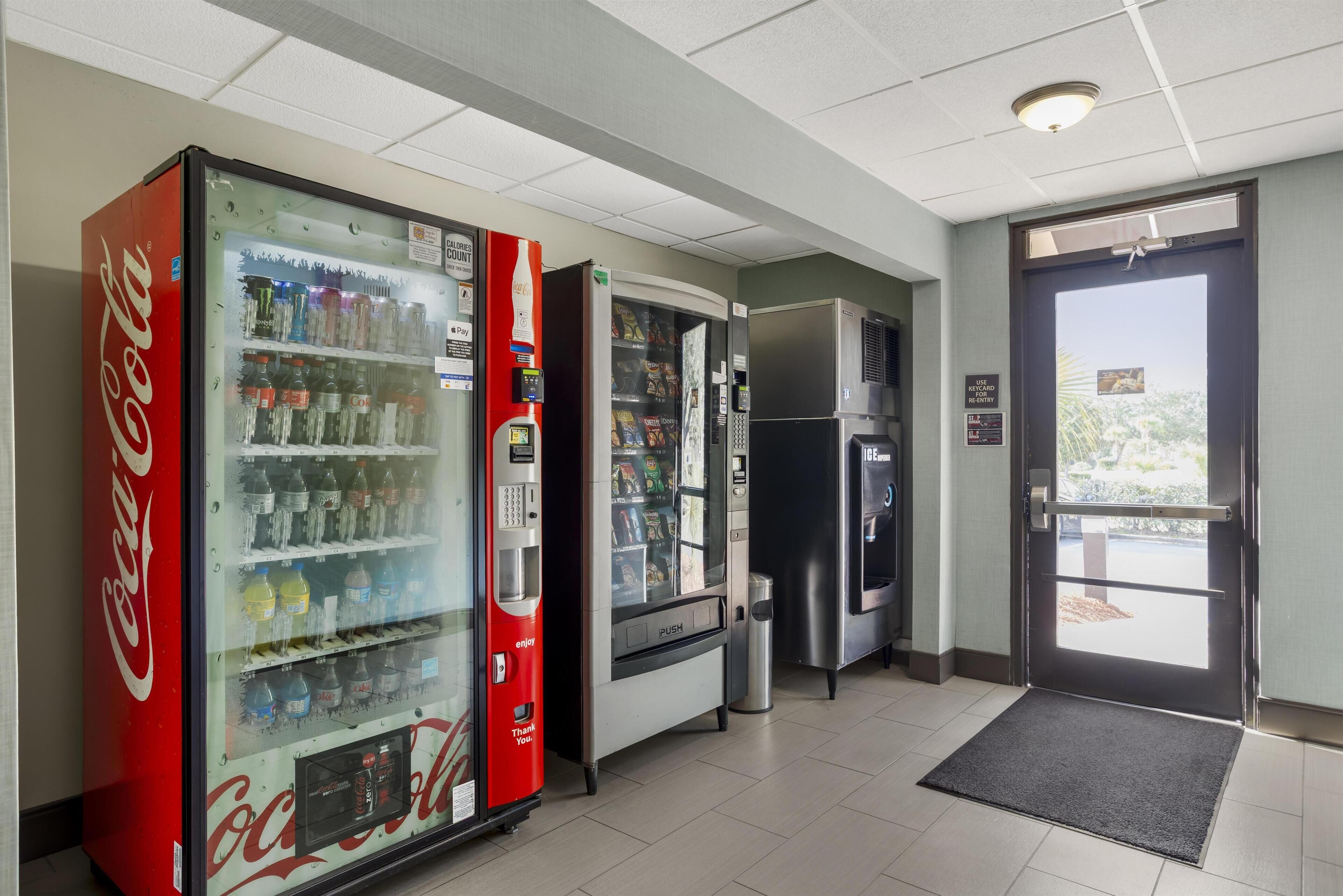 Un espace de vente proposant un distributeur automatique de Coca-Cola, un distributeur d’eau et un réfrigérateur.