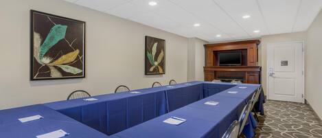 A conference room with a long table, chairs, and artwork on the walls.