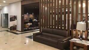 A lobby with a sofa, a table with a lamp, and a bar area. - Hotel Chihuahua San Francisco (Chihuahua)
