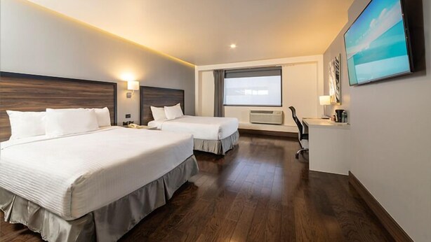 A hotel room with two beds, a desk, a TV, and a window with curtains. - Hotel Chihuahua San Francisco (Chihuahua)