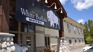 A hotel named "The White Buffalo Hotel" with a buffalo logo, stone pillars, and a wooden porch. - White Buffalo (West Yellowstone)