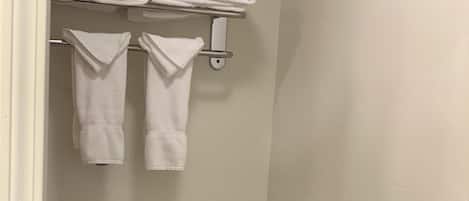 A small, clean bathroom with a toilet, a towel rack with folded towels, and a toilet paper holder.