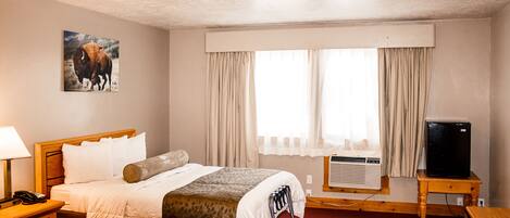 Una camera d'albergo con un letto, una scrivania, una televisione e un condizionatore.