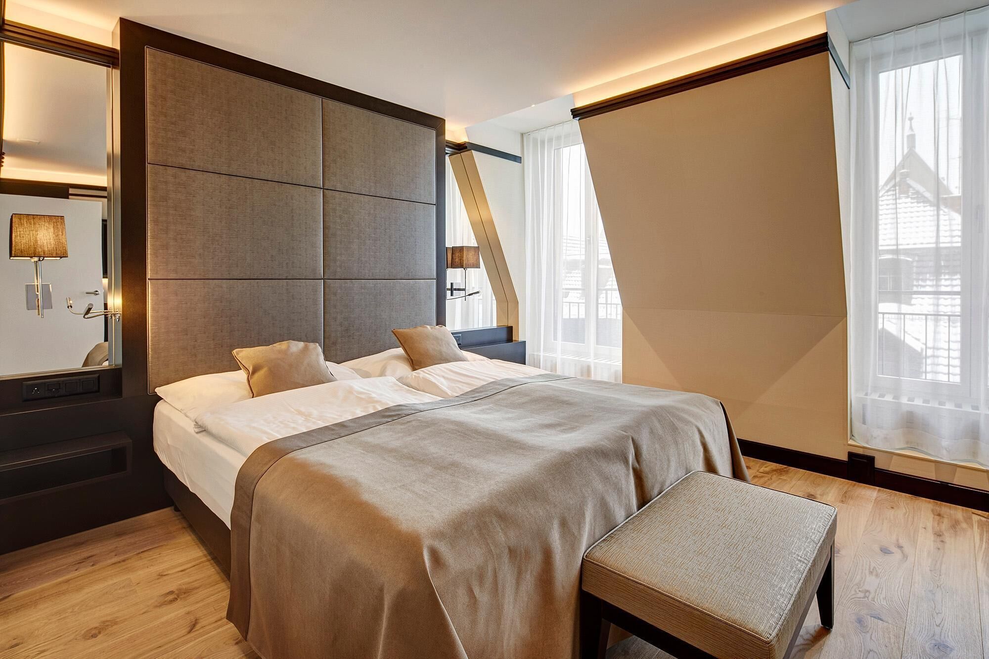 Un dormitorio moderno con una cama grande, una mesita de noche, un espejo y una ventana con cortinas.