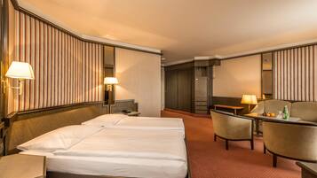 Een hotelkamer met twee bedden, een bureau, een stoel, een bank en een minibar.