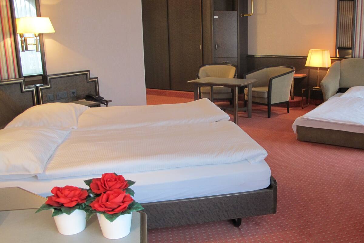 Hotellihuoneessa on kaksi sänkyä, työpöytä, tuoli ja pieni pöytä. Huoneen molemmilla puolilla on lamput.