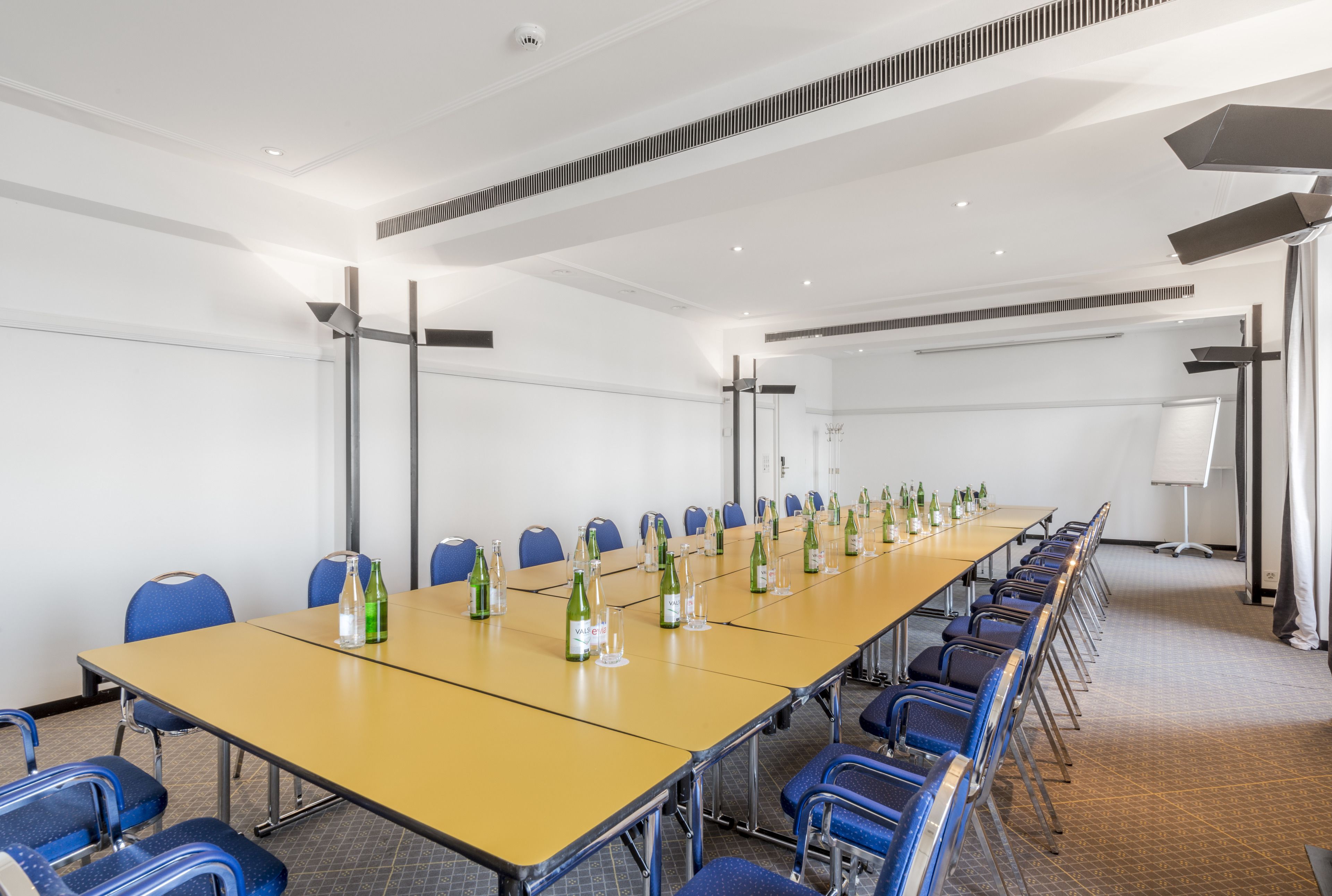 A conference room with a long table, blue chairs, and bottles of water.