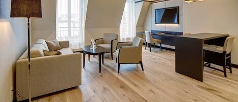 Un salon moderne comprenant un canapé, des fauteuils, une table basse, un téléviseur et un coin repas.