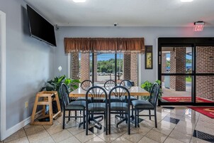 A dining area with a brick wall, a large window, and a view of the parking lot.