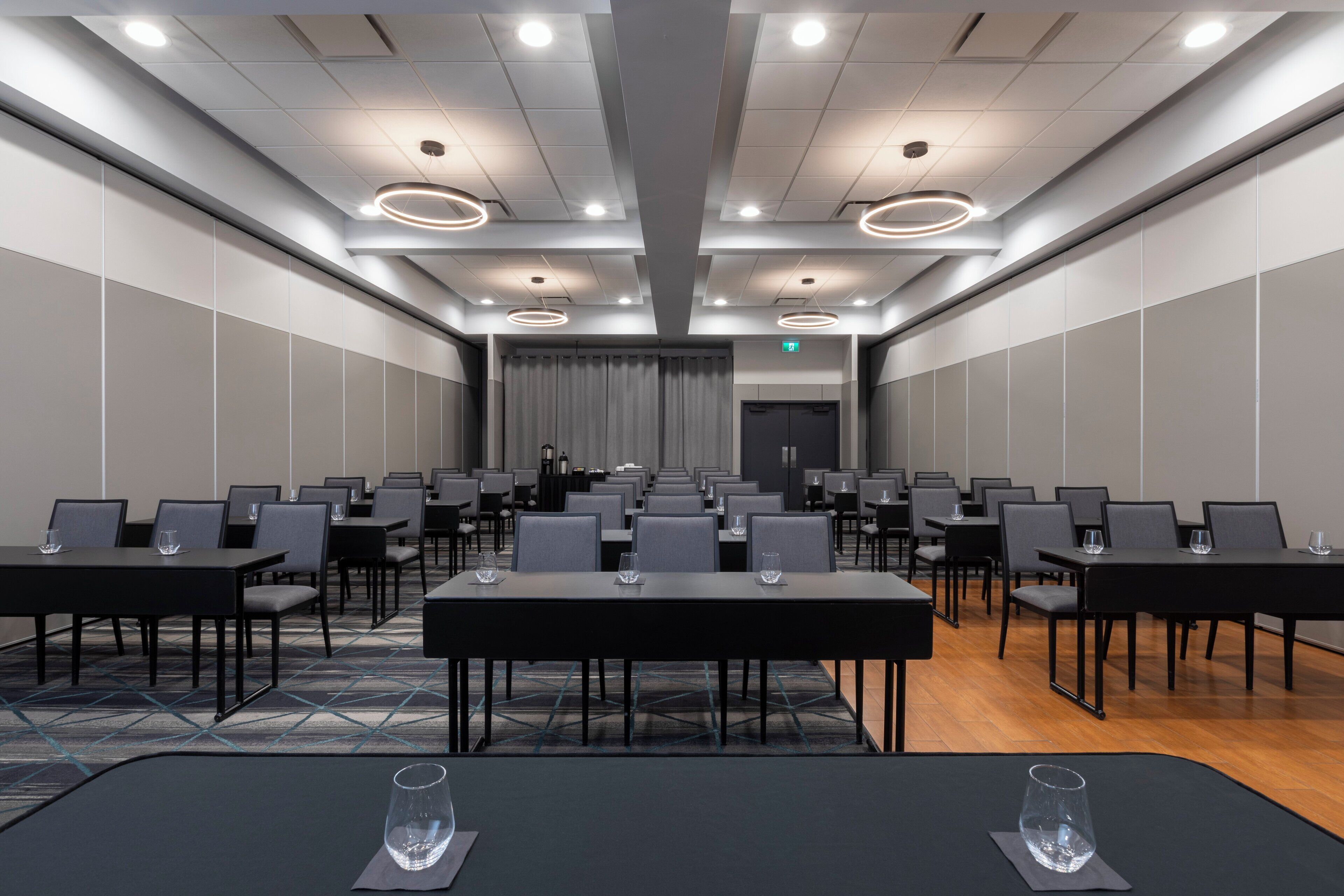 A conference room with rows of tables and chairs, a patterned carpet, and a modern ceiling design.