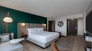 A modern hotel room with a large bed, a desk, a chair, and a TV.