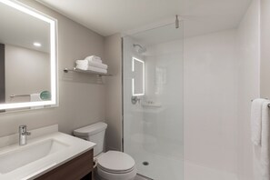 A modern bathroom with a glass-enclosed shower, a white sink, and a toilet.