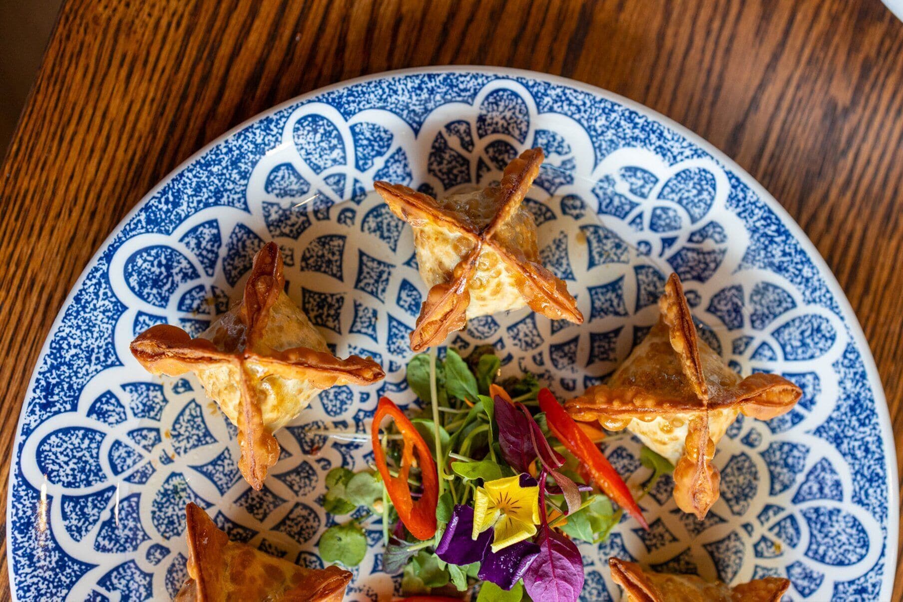 A plate with a blue and white pattern, containing food items and a salad.