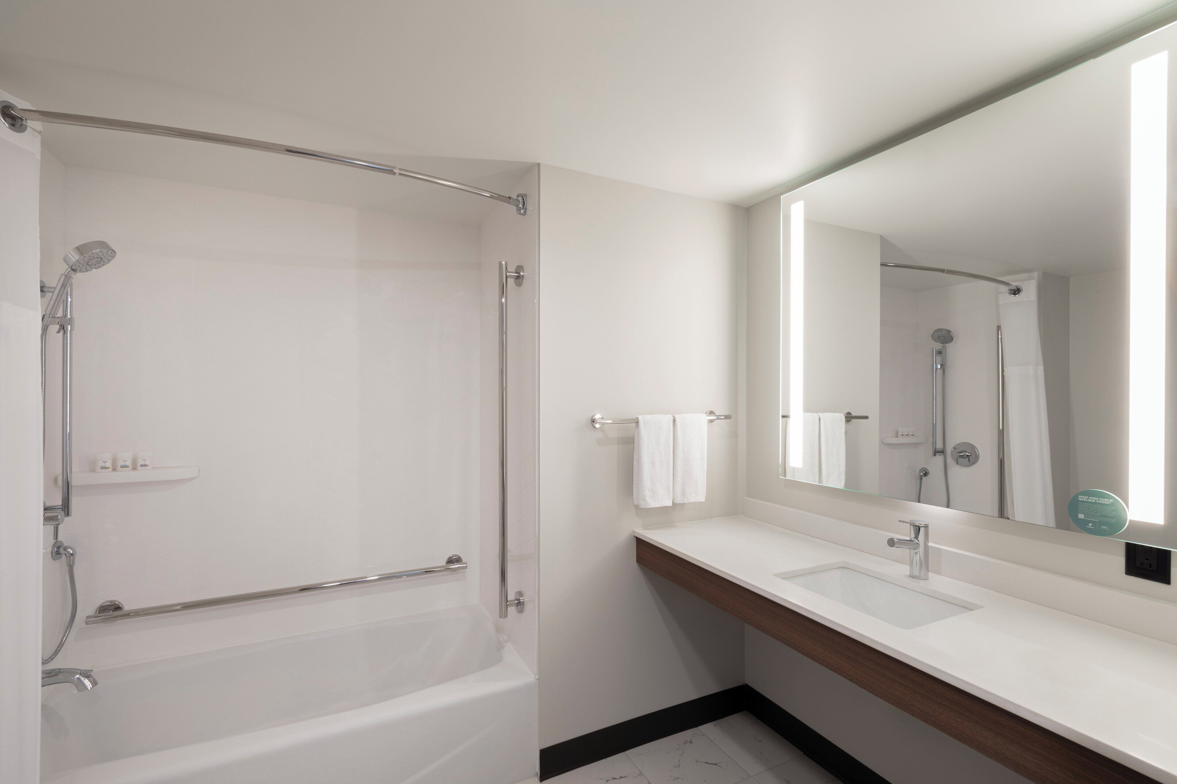 Un bagno moderno con una vasca, un lavandino e un ampio specchio.