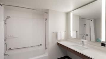 Un bagno moderno con una vasca, un lavandino e un ampio specchio.