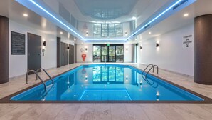 Una piscina interior moderna con normas claras para el uso, techo de cristal y vistas al exterior.