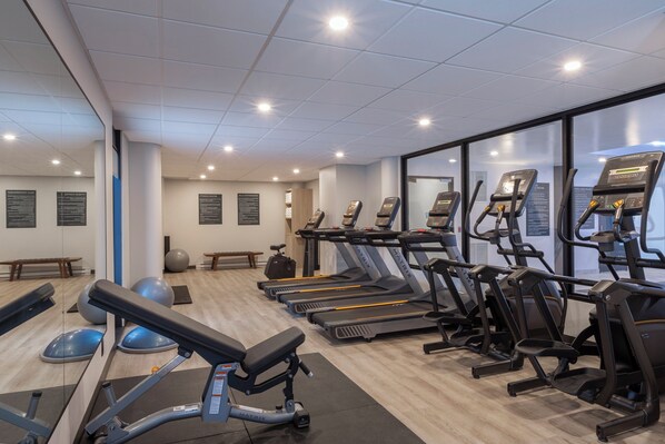 A gym with treadmills, elliptical machines, and exercise balls.