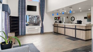 A hotel lobby with a reception desk, a large window with curtains, a ceiling fan, and a potted plant. - Quality Inn Cheyenne I-25 South (Cheyenne)