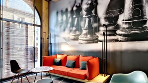 A modern interior with a red sofa, a round table, and a chessboard wall art. - ibis Agen Centre (Agen)