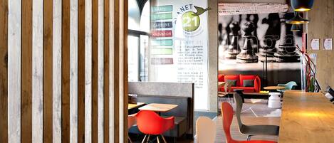 A modern restaurant interior with wooden paneling, red and black chairs, and a wooden counter.